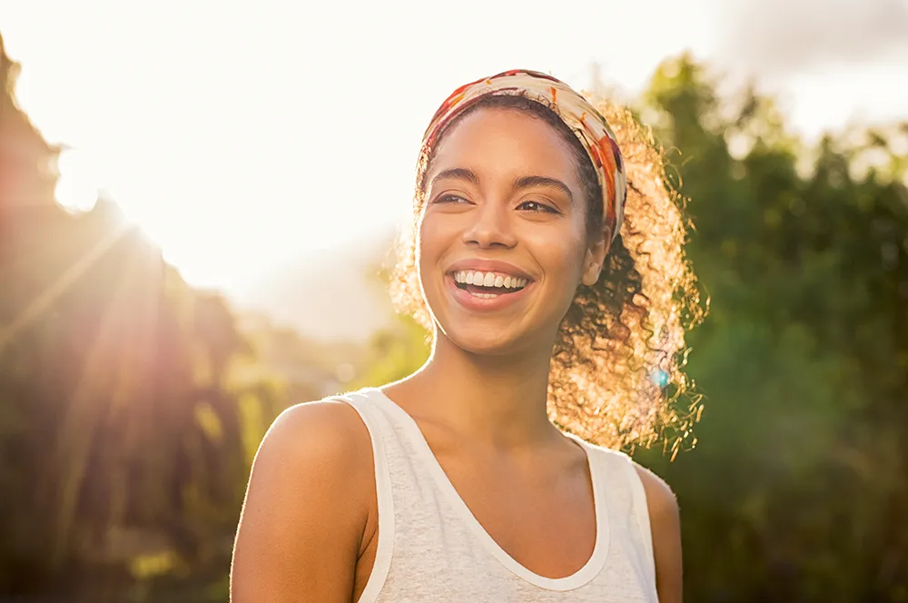 Woman smiling outdoors in warm sunlight